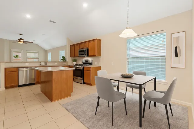 a kitchen with stainless steel appliances granite countertop a stove top oven a sink dishwasher a dining table and chairs with wooden floor