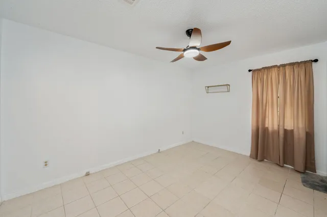 an empty room with windows and fan view
