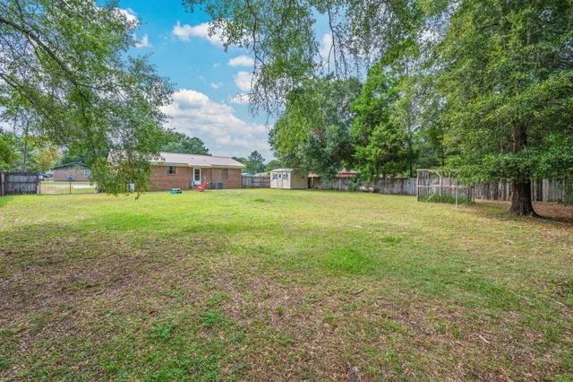 a view of a big yard with a house and large trees with wooden fence