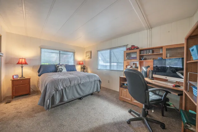 a bed sitting in a bedroom next to a window and a flat tv screen