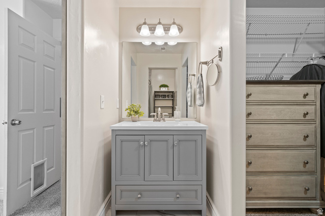 8248 South Resaca Drive, Unit J10 Sandy, UT 84070 - Photo 14 of 40 Modern vanity featuring a gray cabinet with double doors and a bottom drawer, white countertop with an integrated sink, and an overhead three-light fixture