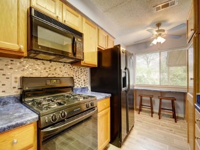 6601 Ripple Run Austin, TX 78744 - Photo 10 of 22 a kitchen with stainless steel appliances granite countertop a stove a refrigerator and a microwave