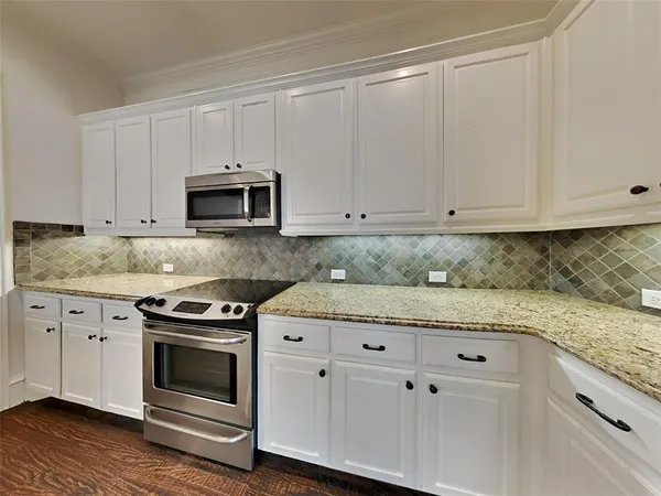 a kitchen with granite countertop white cabinets and stainless steel appliances