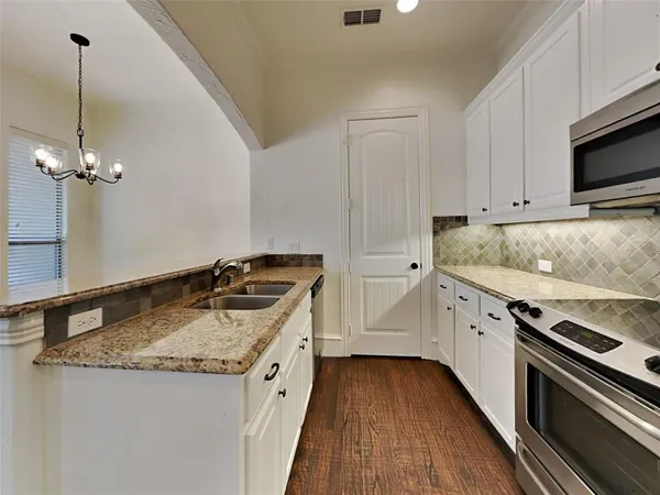 a kitchen with granite countertop a sink stove and cabinets
