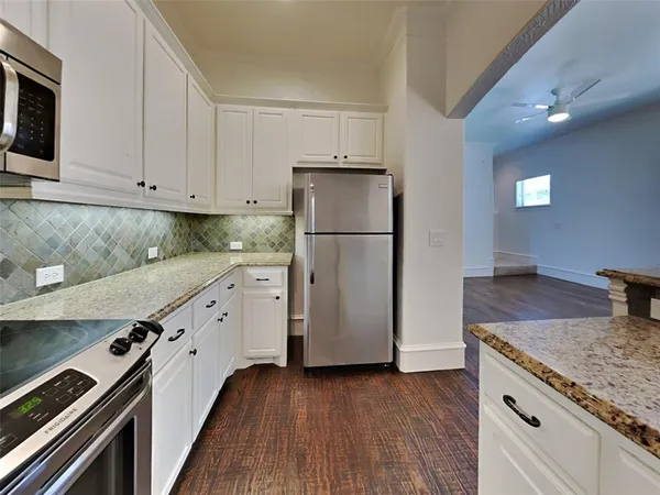 a kitchen with granite countertop a refrigerator and a stove top oven