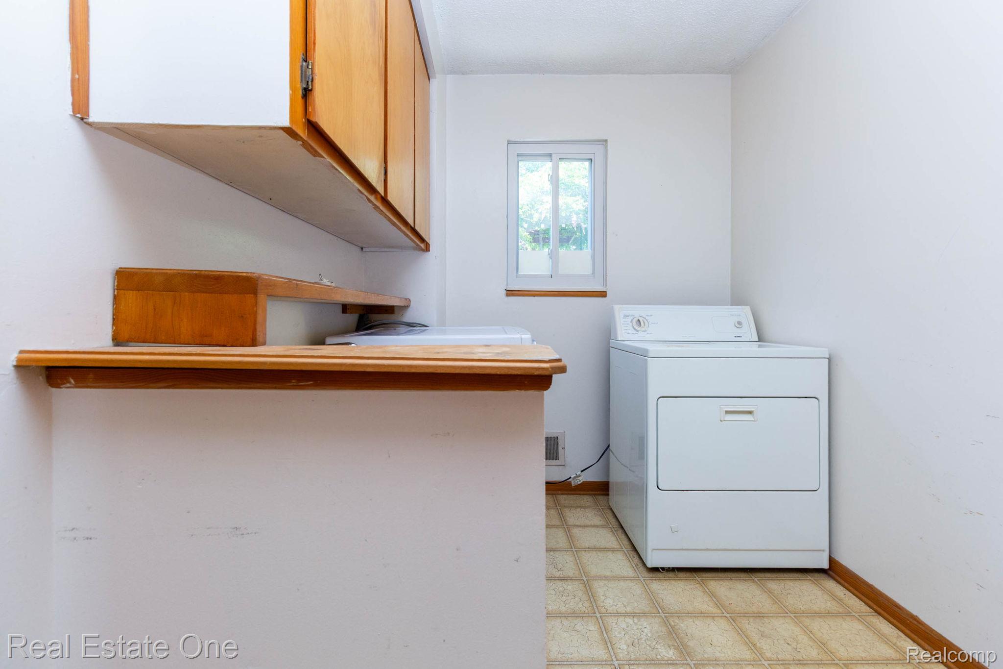 13912 Clinton River Road Sterling Heights, MI 48313 - Photo 23 of 43 Dedicated utility space featuring built-in cabinetry, wood-finish shelving, and a single window