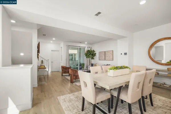 a kitchen with stainless steel appliances granite countertop a stove a sink a refrigerator white cabinets and wooden floor