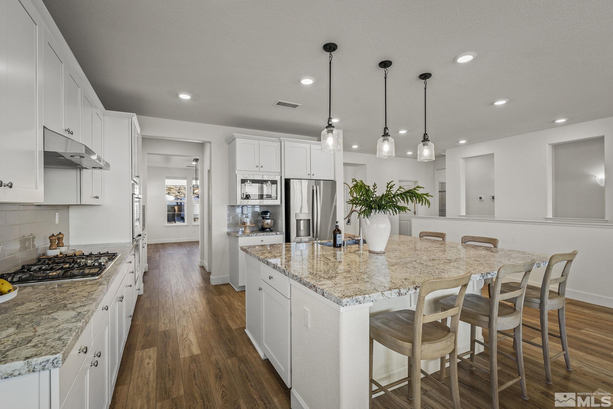10489 Claim Jumper Way Reno, NV 89521 - Photo 16 of 40 a kitchen with stainless steel appliances kitchen island granite countertop a stove a sink and a wooden floors