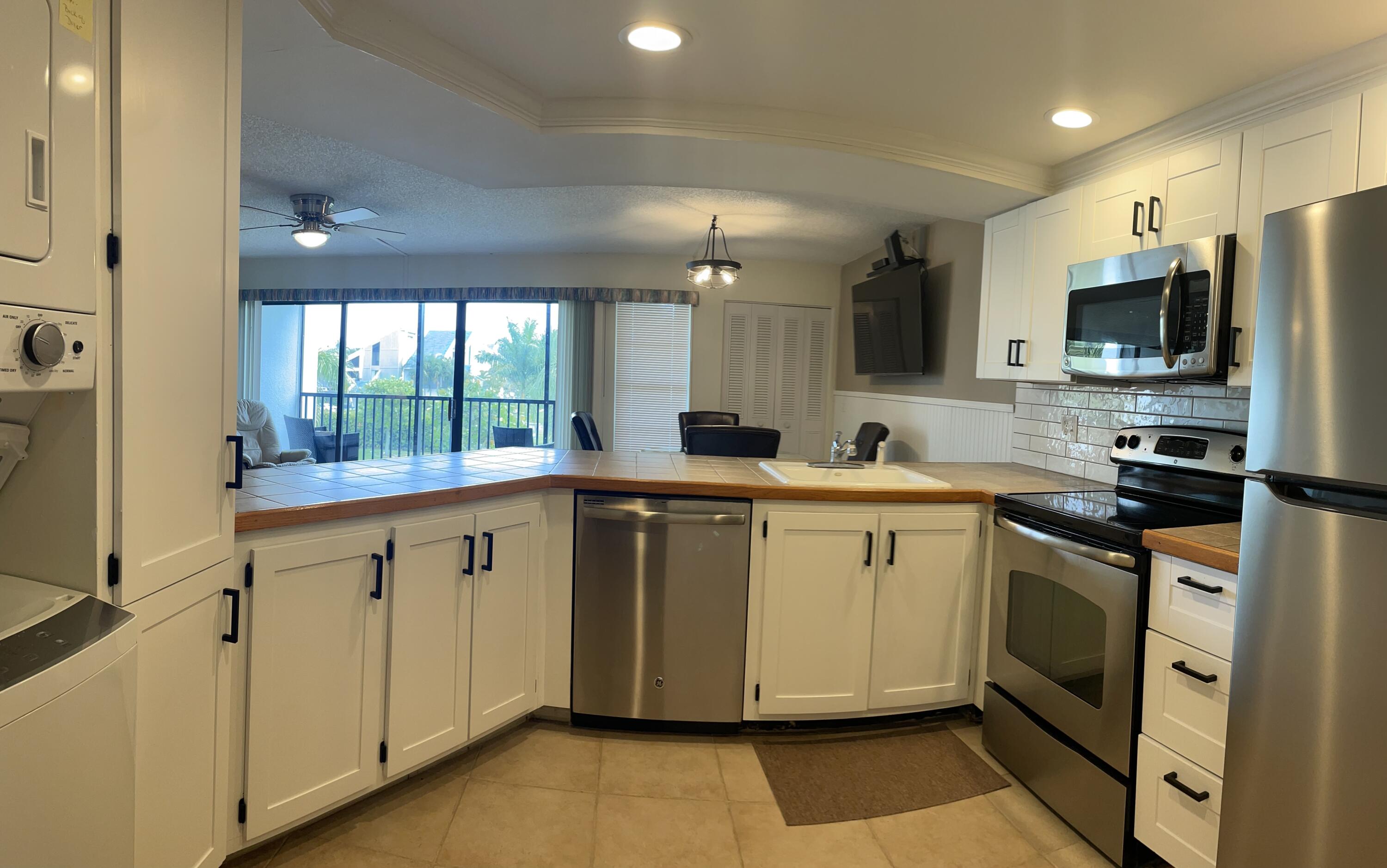 1605 Highway 1, Unit 201V2 Jupiter, FL 33477 - Photo 5 of 9 a kitchen with stainless steel appliances granite countertop a stove a sink and a microwave