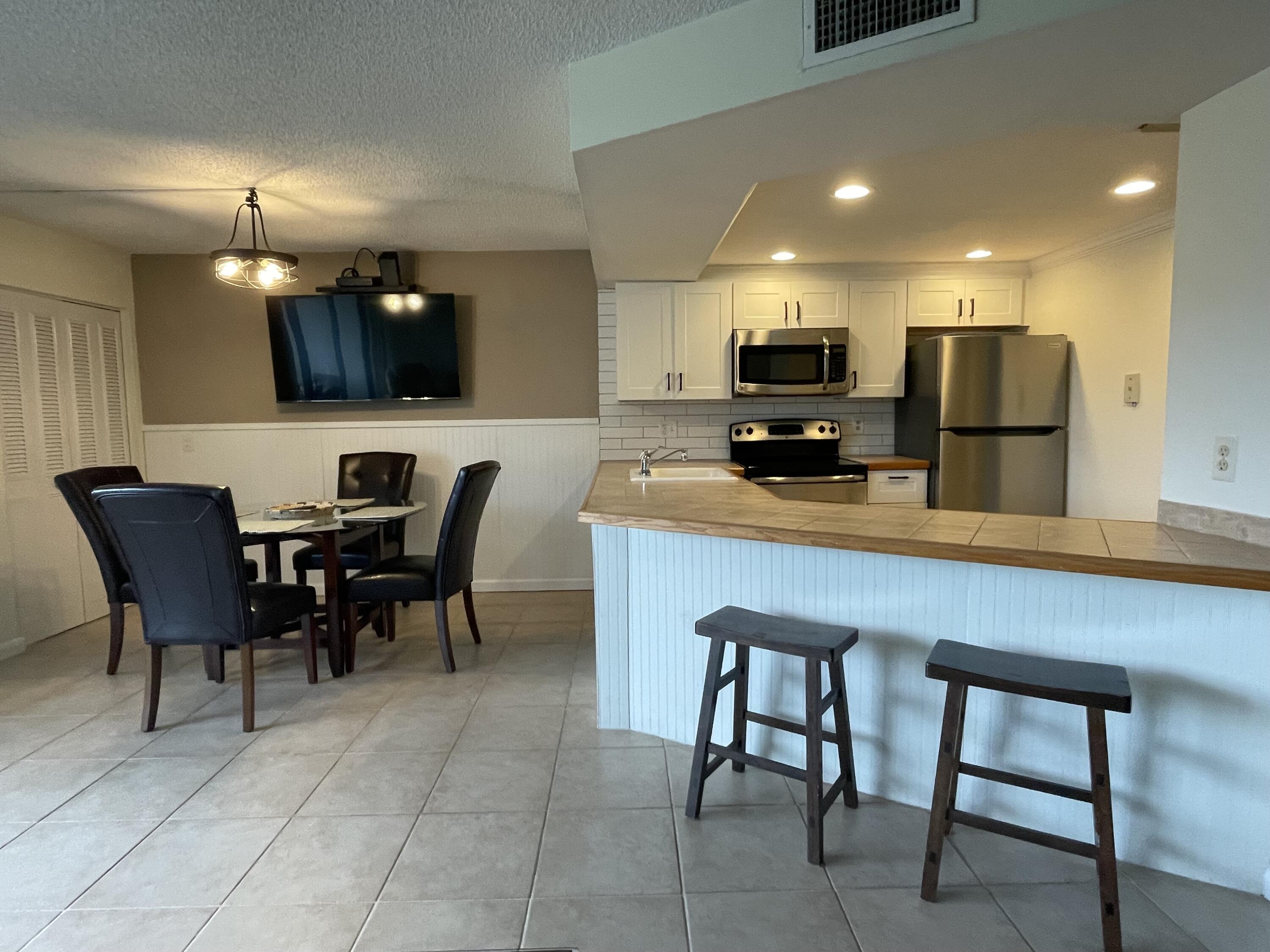 1605 Highway 1, Unit 201V2 Jupiter, FL 33477 - Photo 6 of 9 a kitchen with a dining table chairs and refrigerator