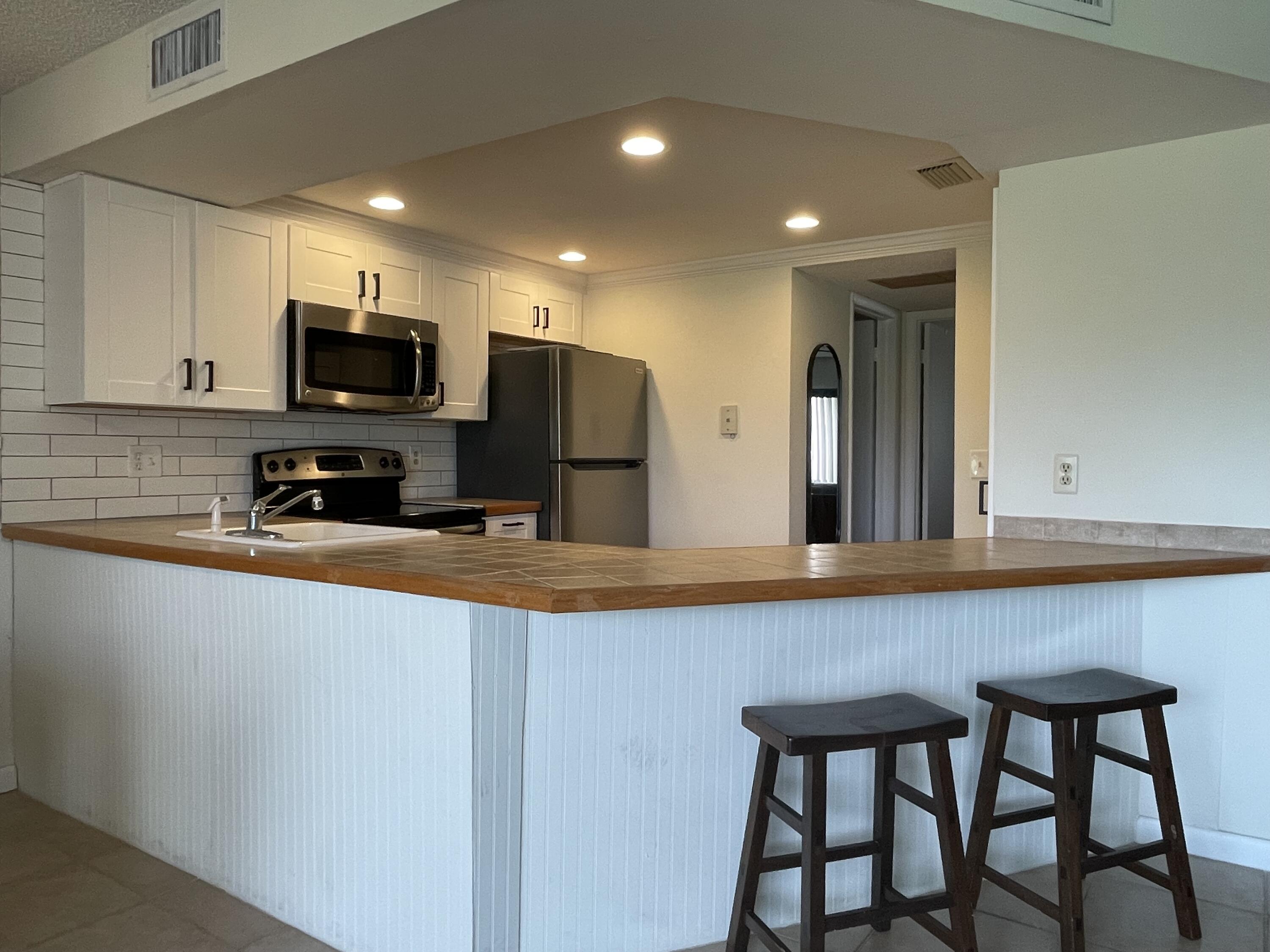 1605 Highway 1, Unit 201V2 Jupiter, FL 33477 - Photo 8 of 9 a kitchen with stainless steel appliances granite countertop a sink a stove a microwave a refrigerator counter space and cabinets