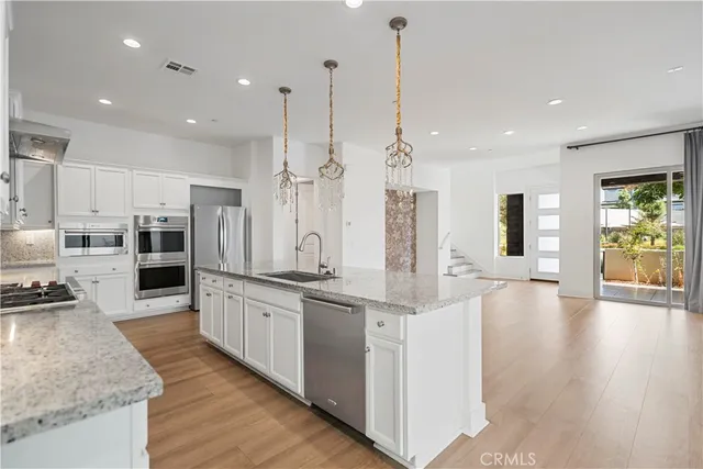 a large kitchen with stainless steel appliances kitchen island granite countertop a large counter top and wooden floors