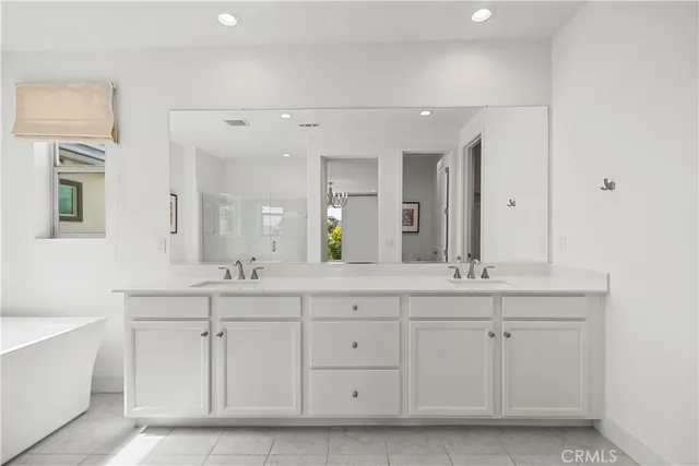 a bathroom with a double vanity sink mirror and bathtub