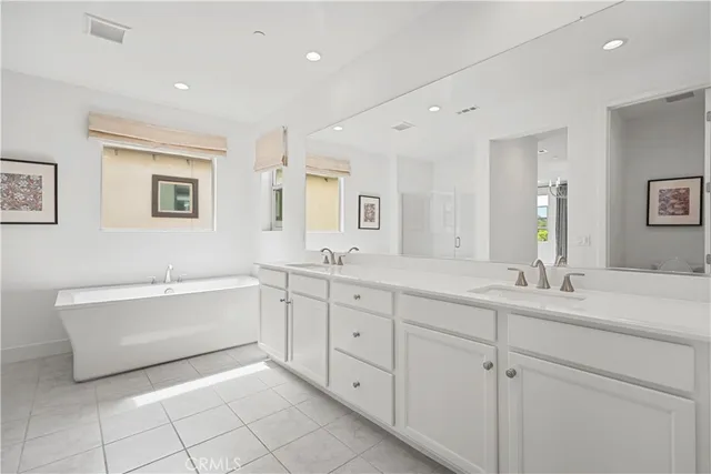 a spacious bathroom with a double vanity sink mirror and bathtub