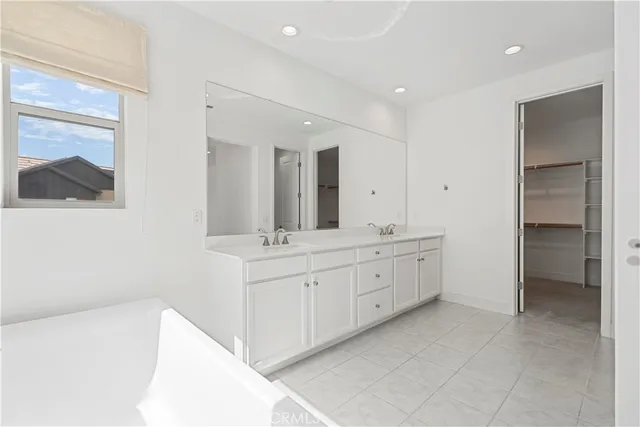a spacious bathroom with a double vanity sink a mirror and a bathtub