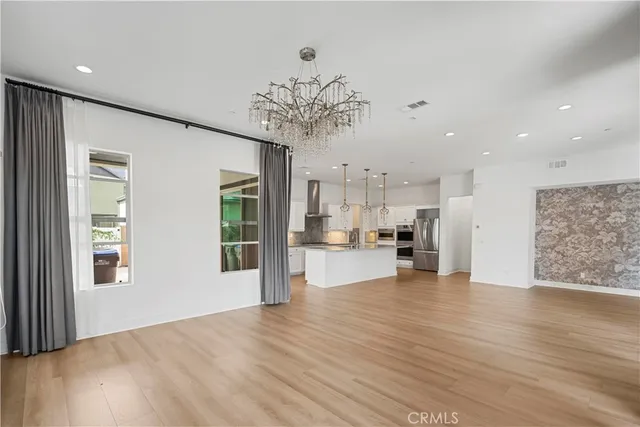a view of an empty room with kitchen and window