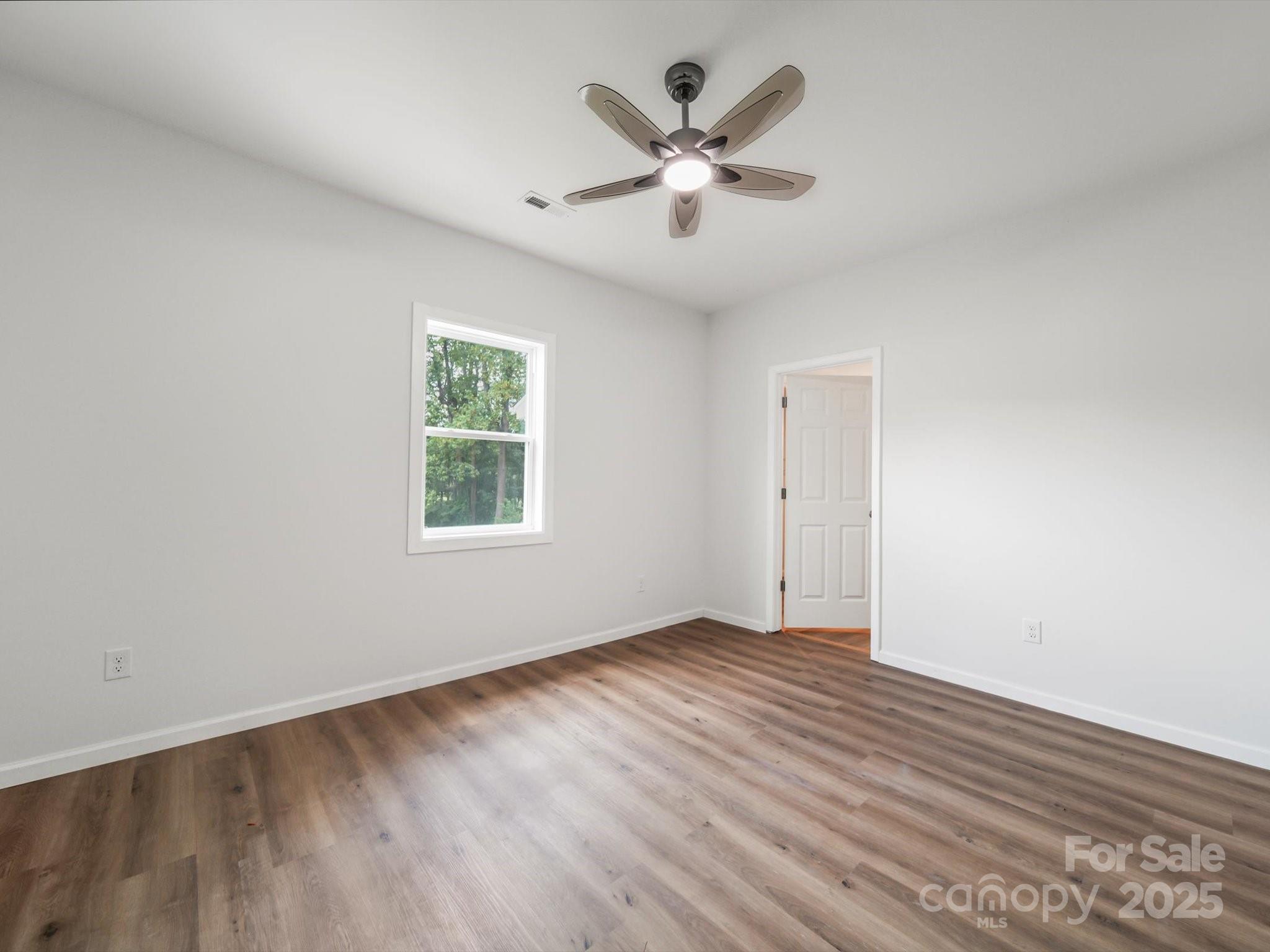 334 South Pink Street Cherryville, NC 28021 - Photo 12 of 25 an empty room with wooden floor chandelier fan and windows
