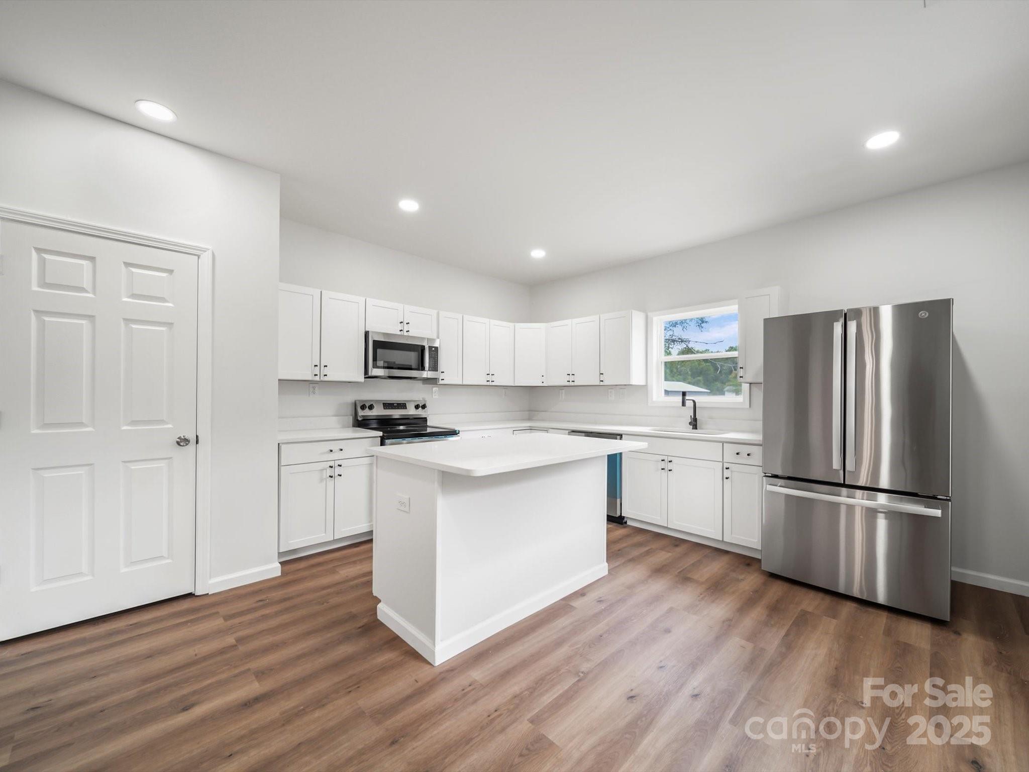 334 South Pink Street Cherryville, NC 28021 - Photo 8 of 25 a kitchen with wooden floors white cabinets and stainless steel appliances