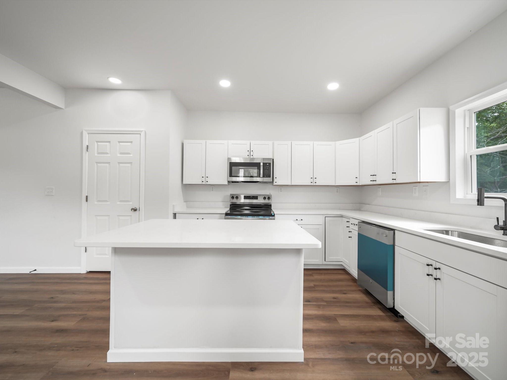 334 South Pink Street Cherryville, NC 28021 - Photo 10 of 25 a kitchen with stainless steel appliances granite countertop a sink a stove a refrigerator and white cabinets with wooden floor