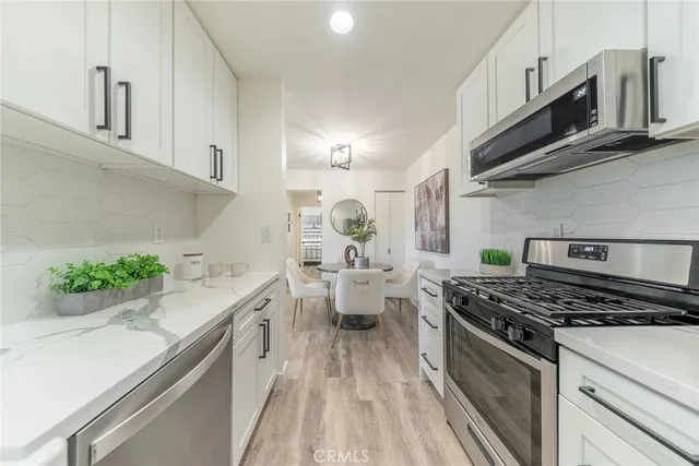 a kitchen with stainless steel appliances kitchen island granite countertop a sink stove and white cabinets
