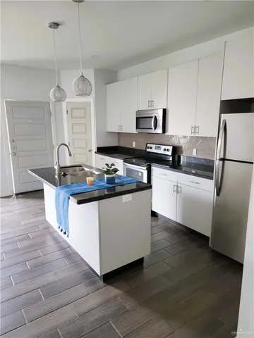 a kitchen with granite countertop a sink a counter top space stainless steel appliances and cabinets
