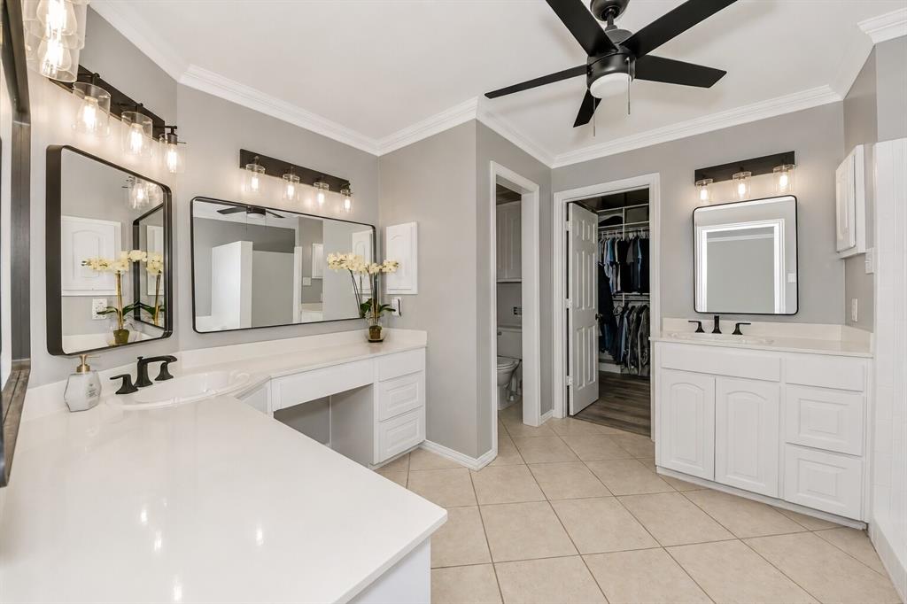 3817 Ganzer Road West Denton, TX 76207 - Photo 27 of 40 This angle shows the primary bathroom’s clean, modern layout with dual vanities and a dedicated three-station vanity on the left — complete with space for a chair, making morning routines feel relaxed and intentional. The finishes stay crisp and timeless with white cabinetry, black fixtures, and soft natural light. Just beyond the doorway, the custom walk-in closet offers generous storage and an easy flow between getting ready and winding down. It’s a bright, functional space designed to feel calm and effortless.