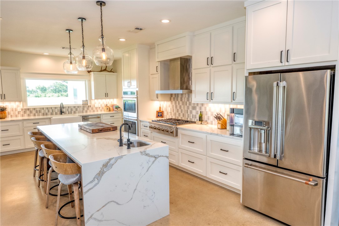 7105 Watermelon Road Somerville, TX 77879 - Photo 12 of 40 a kitchen with stainless steel appliances granite countertop a refrigerator a sink dishwasher a stove and white cabinets with wooden floor