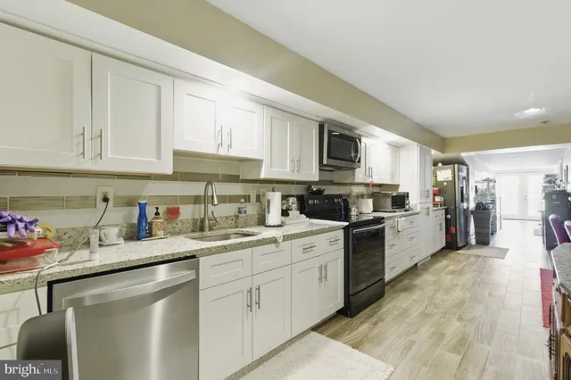 a kitchen with stainless steel appliances granite countertop a sink dishwasher stove top oven and cabinets with wooden floor