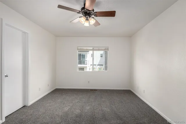 an empty room with a window and a fan