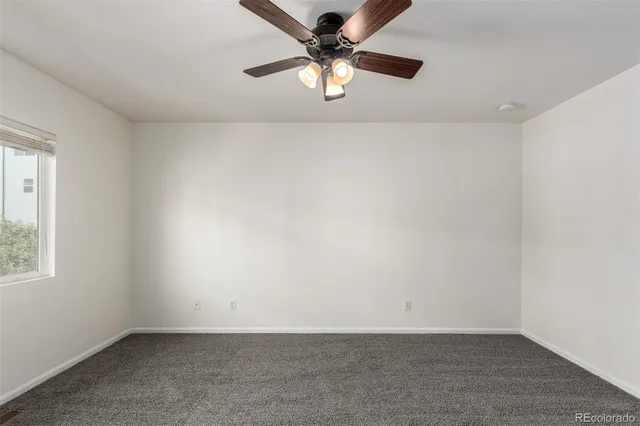 an empty room with a window and a ceiling fan