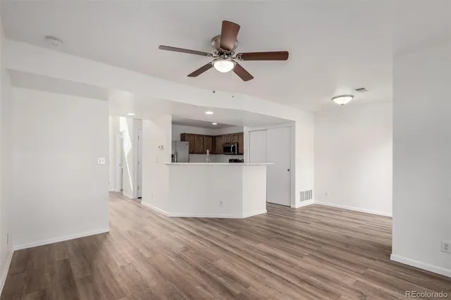 a view of empty room with wooden floor and ceiling fan