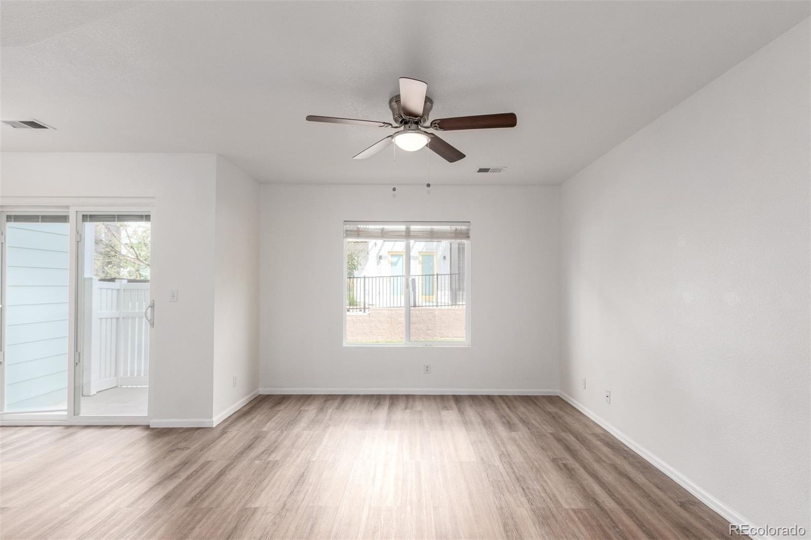 5850 Ceylon Street, Unit D Denver, CO 80249 - Photo 6 of 33 an empty room with wooden floor ceiling fan and windows