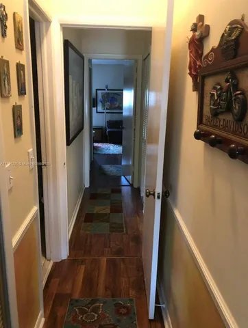 a view of a hallway with wooden floor and a bathroom