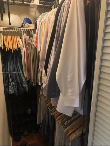 a view of walk in closet with clothes and shoes