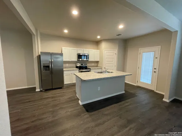 a large kitchen with kitchen island a sink dishwasher a refrigerator and wooden floor