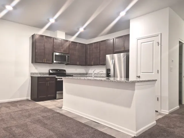 a large kitchen with kitchen island granite countertop wooden cabinets and a granite counter tops