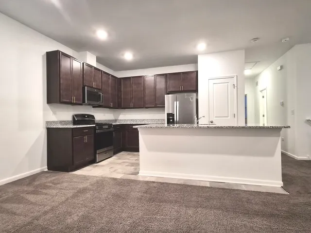 a view of kitchen with granite countertop cabinets and refrigerator