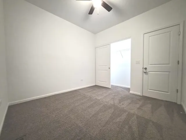 an empty room with closet and a chandelier fan