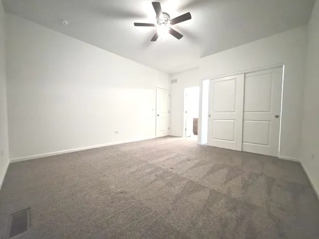 an empty room with chandelier fan and windows