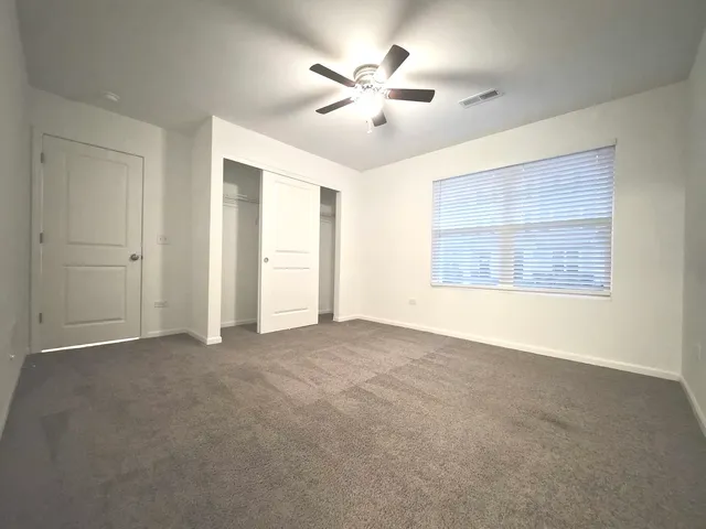 an empty room with chandelier fan and windows