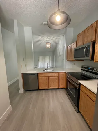 a large kitchen with stainless steel appliances a large counter top a stove a sink and a refrigerator