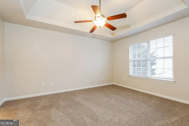 an empty room with ceiling fan and window