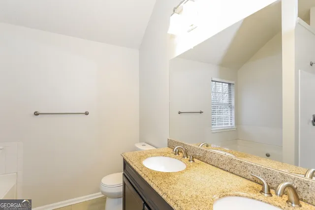 a bathroom with a granite countertop sink a toilet and mirror