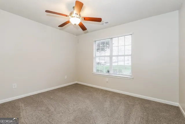 an empty room with a window and a fan