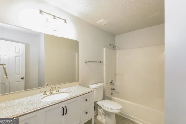 a bathroom with a granite countertop sink a toilet and shower