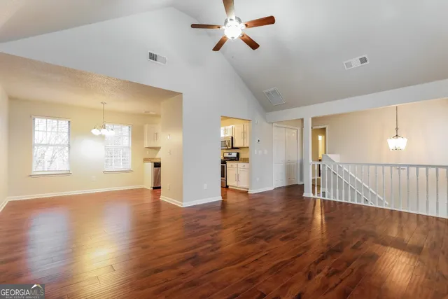 a view of an empty room with wooden floor and a window