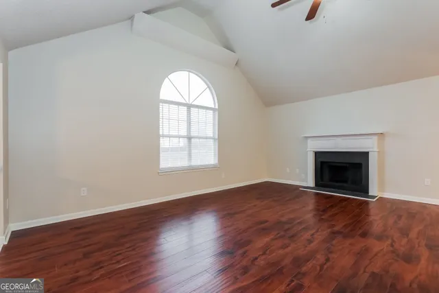 an empty room with wooden floor a fireplace and windows