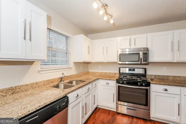 a kitchen with granite countertop white cabinets and appliances