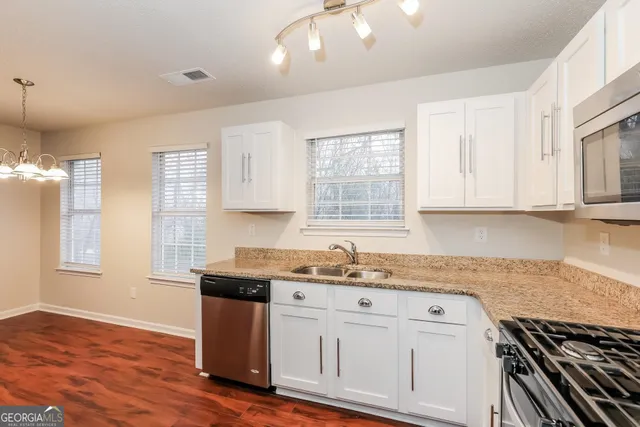 a kitchen with stainless steel appliances granite countertop a sink dishwasher a stove and a refrigerator