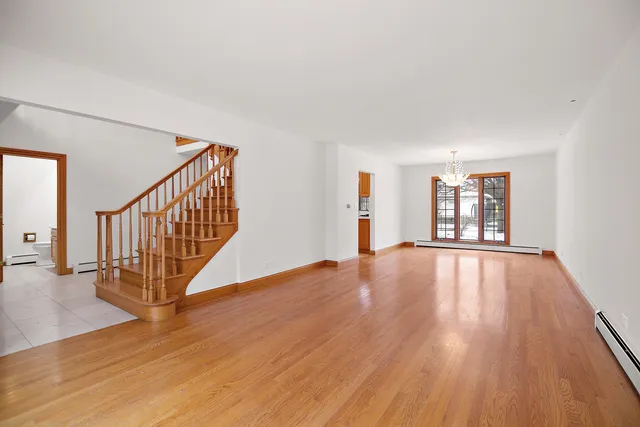 a view of an empty room with wooden floor and fan
